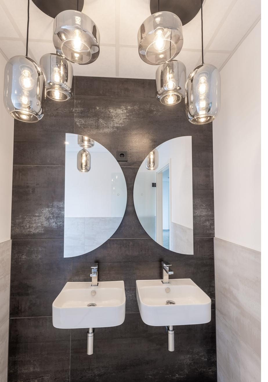 Neuer Sanitärbereich mit Design-Waschtischen, runden Spiegeln und Pendelleuchten